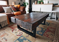 Mesa de centro en durmientes de tren recuperados con base de fierro negro, diseño robusto y estilo industrial contemporáneo.